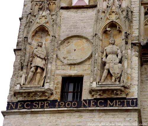 Stadhuis en belfort AALST foto De twee halfverheven beelden op de voorgevel van de Belforttoren stellen de Graven van Vlaanderen en de Graven van Aalst voor.   De zonnewijzer tussen de twee beelden was aanvankelijk zo oud als de belforttoren zelf. In 1600 werd echter een nieuwe zonnewi