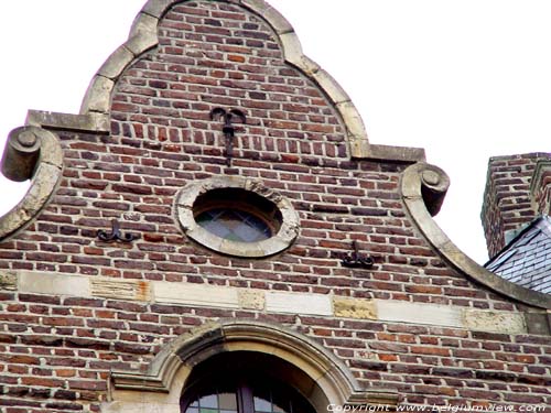 Den Swaen MAASEIK foto De geveltop met speklaag en oculus in mergelsteen, contrasterend met rode baksteen.