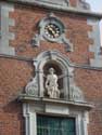 Sint-Rochuskerk (te Sombeke) WAASMUNSTER / BELGIË: Beeldnis en uurwerk obven de ingang, versierd door voluten.
