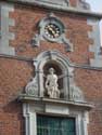 Sint-Rochuskerk (te Sombeke) WAASMUNSTER foto: Beeldnis en uurwerk obven de ingang, versierd door voluten.