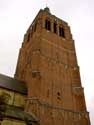 : Massieve, bakstenen westertoren met schietgaten.